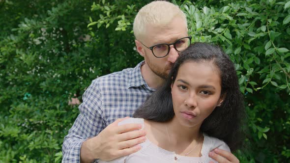 A Young International Interracial Couple in Love Looks Straight in To the Camera on a Sunny Day at