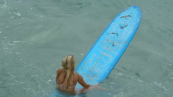 A young woman surfing in a bikini on a longboard surfboard.