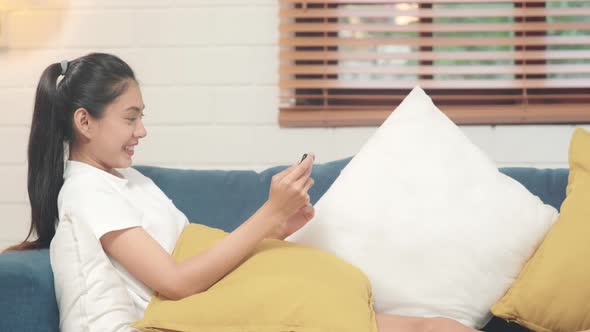 Young Asian woman using smartphone checking social media feeling happy smiling