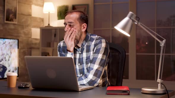 Tired Manager Yawning in Front of His Laptop