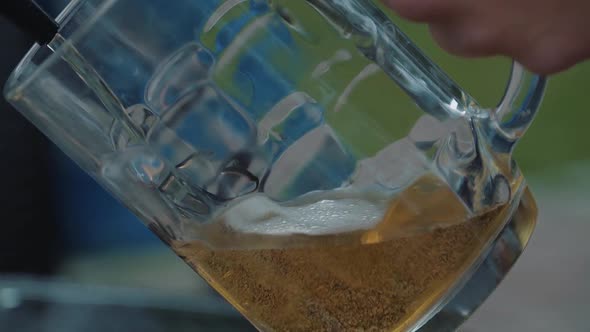 Young Man Pours Beer Into a Mug From a Tap