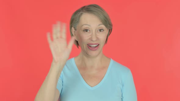 Old Woman Waving Hand to Say Hello on Red Background