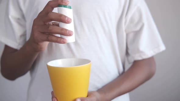 Young Man Putting Artificial Sweetener in Tea