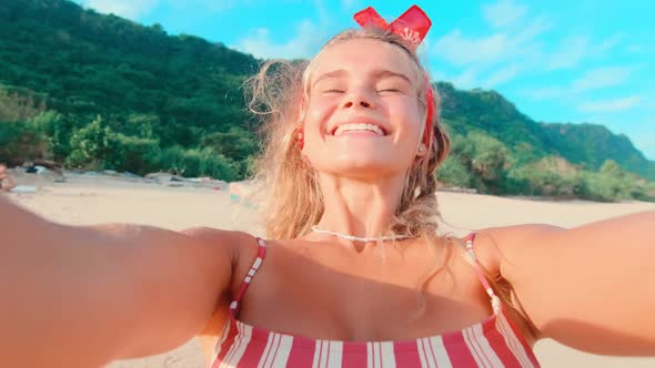 Young Caucasian Woman Twirling Stands on Beach Filming Yourself on Phone Camera