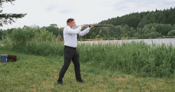 Man Shooting the Gun Outdoors in the Forest Near the River