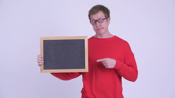 Stressed Young Man Holding Blackboard and Giving Thumbs Down