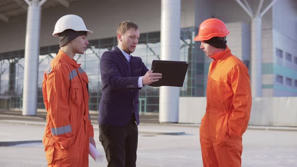 Investor of the Project in a Black Suit Examining the Building Object with Construction Workers in