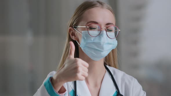 Caucasian Woman Doctor in Glasses and Face Medical Mask in Clinic Hospital Looking at Camera Showing