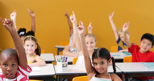 School kids raising hands in classroom