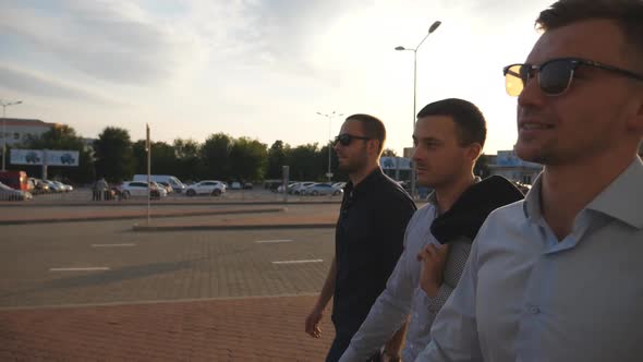 Three Young Businessmen Walking in City with Sun Flare at Background