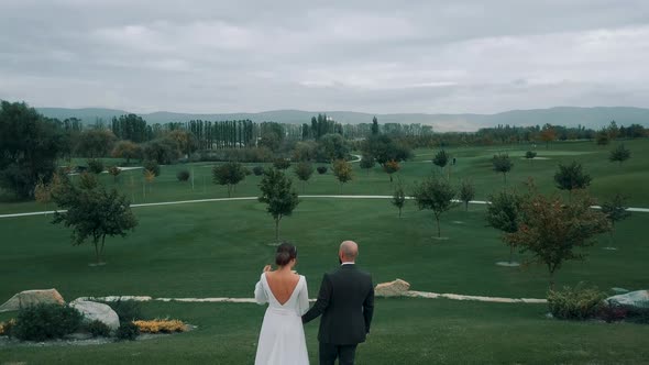 Newlyweds on the background of a beautiful landscaped garden with trees and a cloudy sky