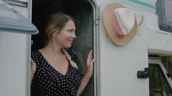 Smiling woman enjoyng vacation and standing in motor home RV campervan.