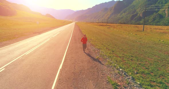 Low Altitude Flight in Front of Sporty Man at Perfect Asphalt Road