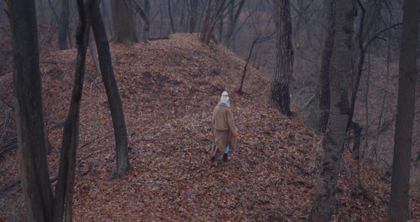 Woman in Winter Clothes Walking Hills in the Rainy Wood