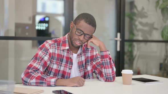 Sleepy African Man Taking Nap While Sitting in Office