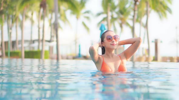 Young asian woman enjoy around outdoor swimming pool for leisure