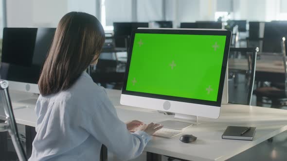 Business Multiethnic Woman Working on Desktop Computer with Green Screen Mock Up Display in Busy