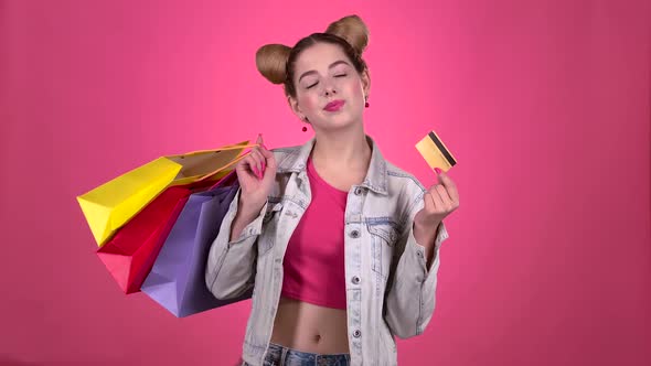Teen Holds Shopping Bags and a Gold Credit Card. Pink Background