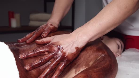 Closeup of Masseur Doing Massage with Chocolate Scrub