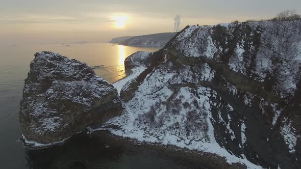 View From a Drone on a Snowcovered Rocky Seashore at Sunset