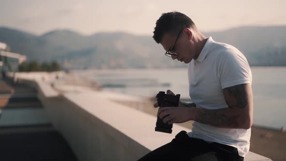 Stylish Photographer in Sunglasses Looking at Photos on Digital Camera