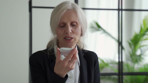 Elderly Woman Holding a Smartphone While Recording a Voice Message to Her Friend