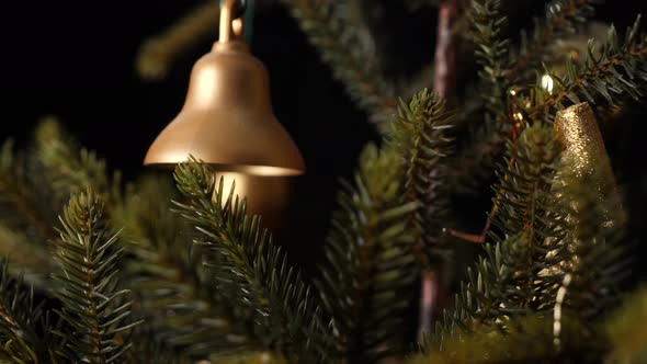 Christmas jingle golden bell hanging on a tree, sliding shot