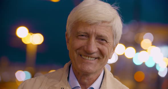 Bokeh Shot of Happy Mature Man Looking at Camera Outdoor