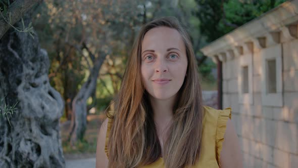 Portrait  of young Woman in a yellow t-shirt looking at camera against the background of nature