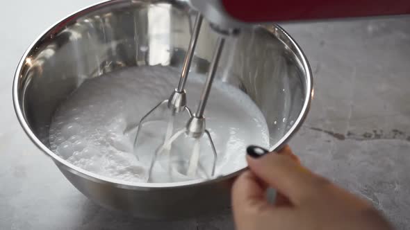 Woman Hands Mixing white Egg Cream in Bowl Using Motor Mixer