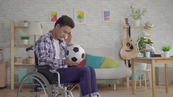 Sad Young Asian Man Disabled in a Wheelchair Former Athlete Football Player with a Soccer Ball