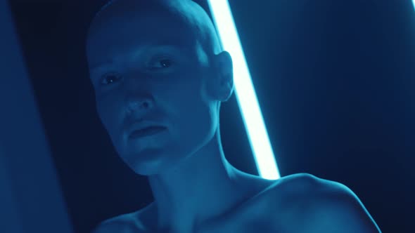 Hairless Female Model Posing in Dark Studio with Flickering Neon Light