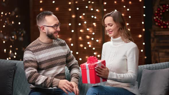 Happy Man Giving Red Gift Box to Woman Congratulating Holiday