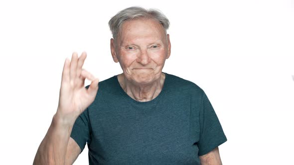 Portrait of Cheerful Retired Man 80s Having Gray Hair and Blue Eyes Smiling While Showing Ok Symbol