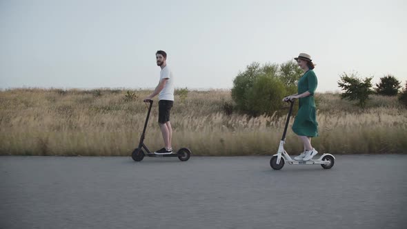 Couple Enjoying and Having Fun While Riding Electric Scooters on Nonurban Road