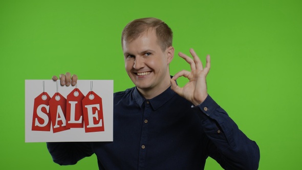 Happy Man Holding Sale Word Inscription and Showing Ok Sign. Guy Rejoicing with Good Sale Discounts