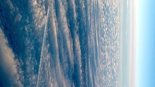 Amazing view from cockpit of flying airplane above clouds leaving long white condensation vapor air