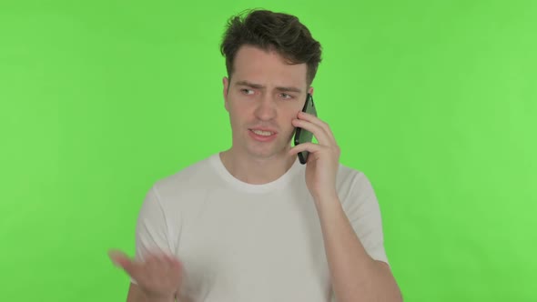 Angry Young Man Talking on Phone on Green Background