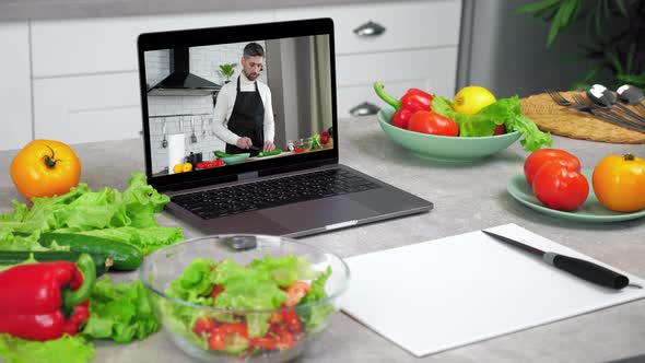 Laptop Computer with Man Chef Food Blogger Slices Cucumber Tells Teaches Student