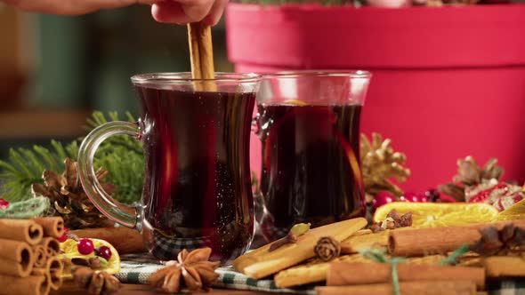 Putting Cinnamon Into Hot Wine in Glass Mugs Gluhwein Closeup