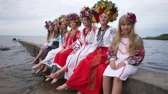 Wide Shot Positive Ukrainian Women and Girl Sitting on River Pier Looking at Camera Smiling