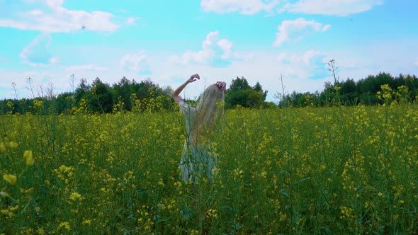 Young Beautiful Girl in a White Dress Straightens Her Long Loose Hair with Her Hands in a Flowering