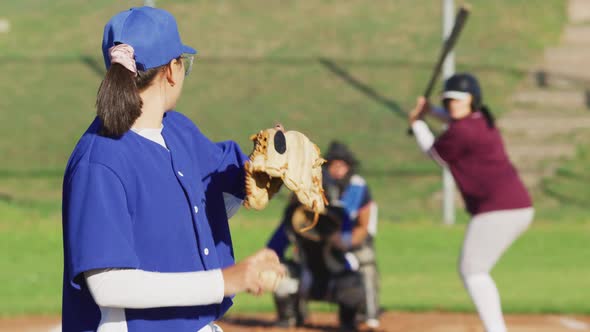 Diverse group of female baseball players in action on the field, pitched ball caught by catcher