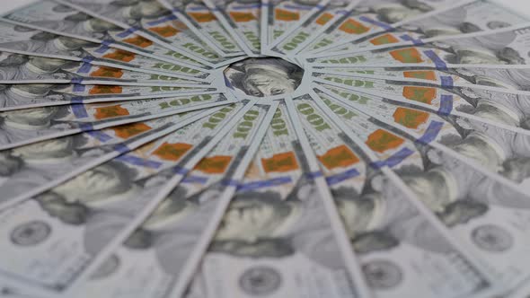 A Closeup of Many Hundreddollar Bills Lie in an Even Circle and Slowly Rotate