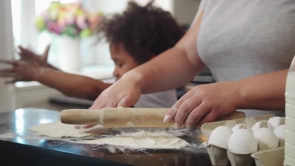 Little Black Girl with Her White Mother Working with Raw Dough in the Kitchen