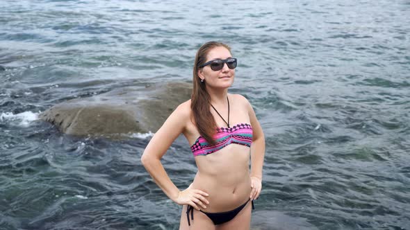 Lady Poses Standing Against Boundless Ocean Washing Rocks