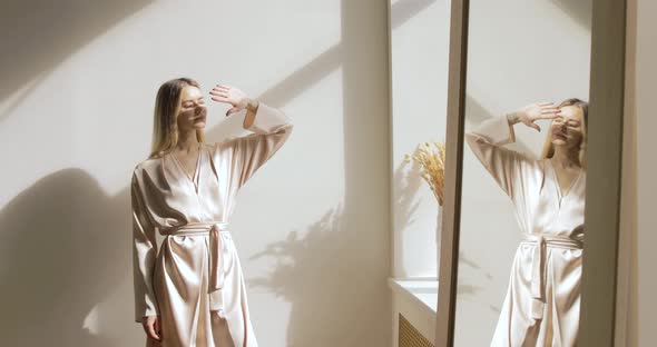 Blonde Model Posing On A White Wall Background And Hiding Her Face From The Sun