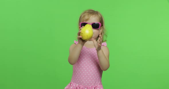 Child in Pink Swimsuit and Sunglasses Eats a Green Pear. Chroma Key