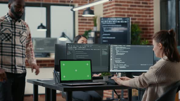 Programer Working at Desk with Multiple Computer Screens and Laptop with Green Screen Chroma Key