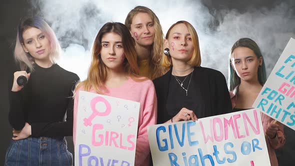 Group of Young Caucasian Feminists with Posters Stand Laughing and Smiling Isolated in Smoky Space